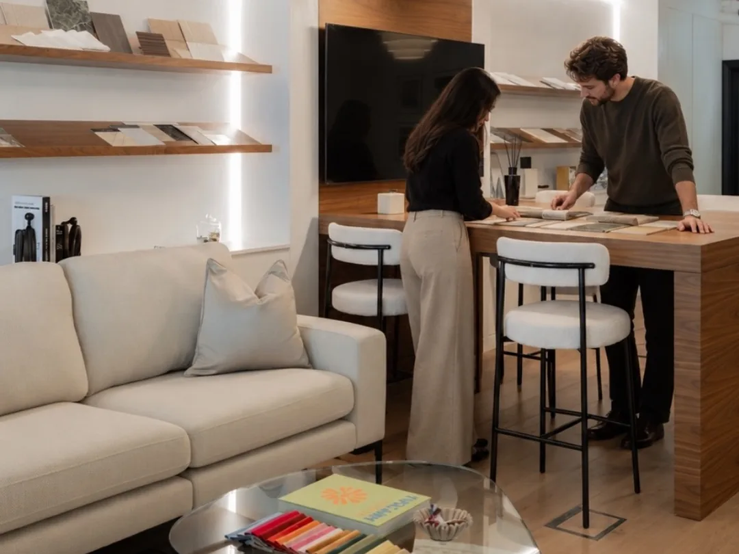 Two Oryx Design designers at the table in the Dubai office, with material samples on the shelves behind them